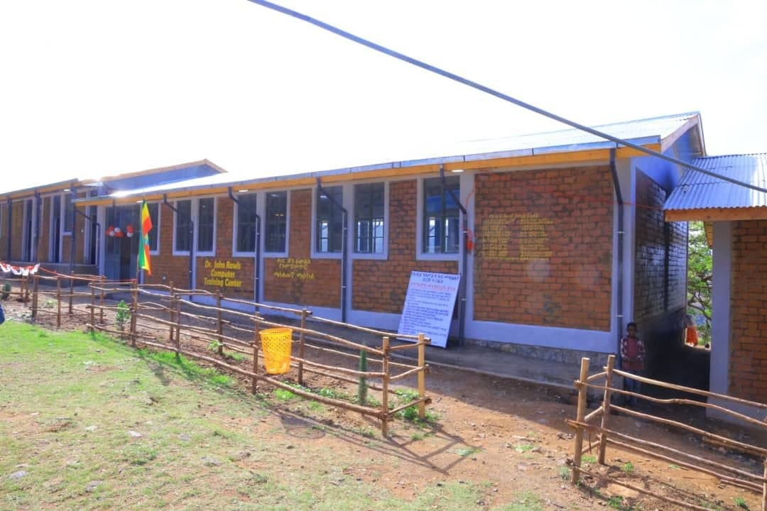 Exterior architectural view of the Dr. John Rawls Computer Training Center building in Gondar with Ethiopian flag flying